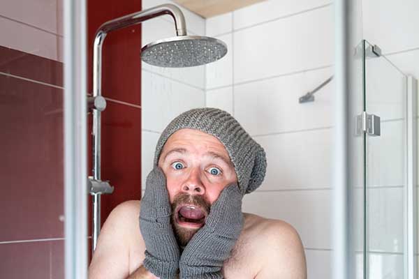 a guy wearing mittens and knit cap in a freezing cold shower